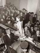A stripper at a Tokyo striptease show is taken past the audience on a moving conveyor belt, 1957.